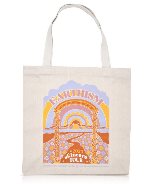 Graphic Earthism grocery bag style cloth tote bag with handles. Graphic is flowery landscape with winding road leading to a modern sun filled sky.