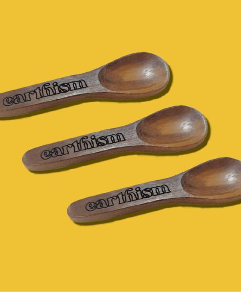 Earthism wooden spoons on yellow background.